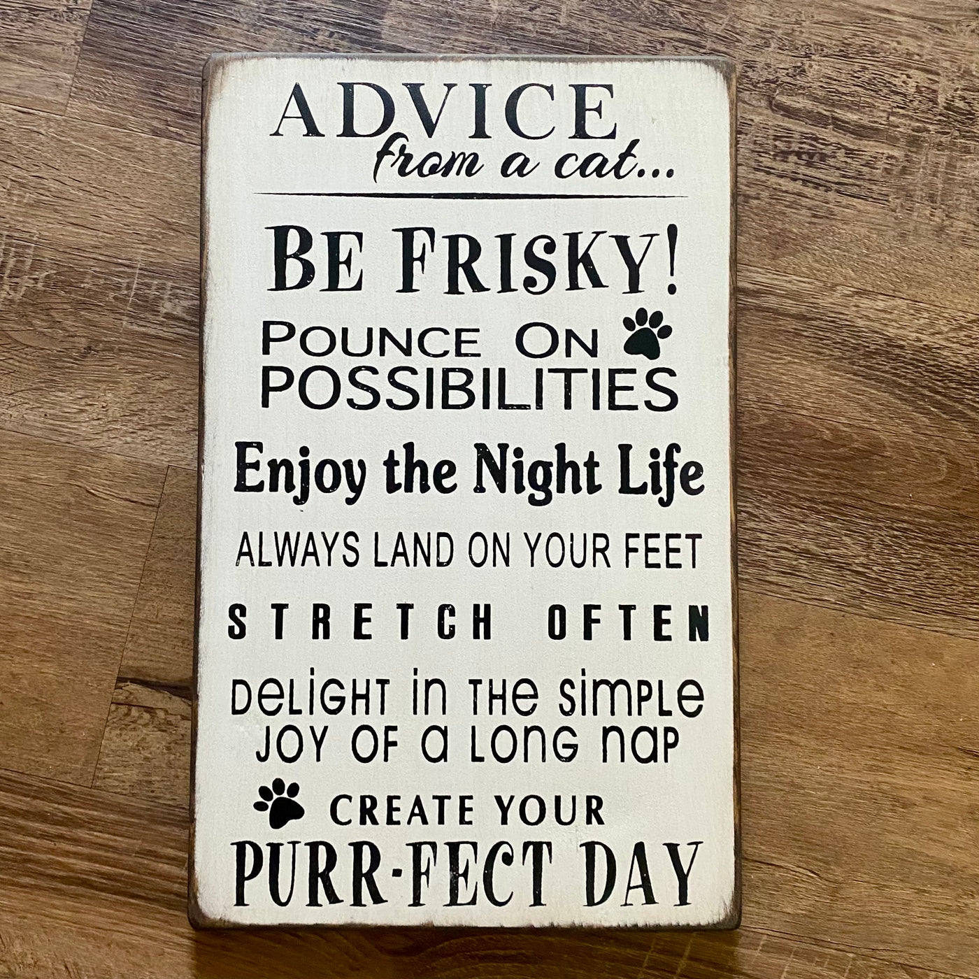 Wooden sign reads advice from a cat.. Be frisky! Pounce on Possibilities, enjoy the nightlife, always land on your feet, stretch often, delight in the simple joy of a long nap, create your purrfect day. 
