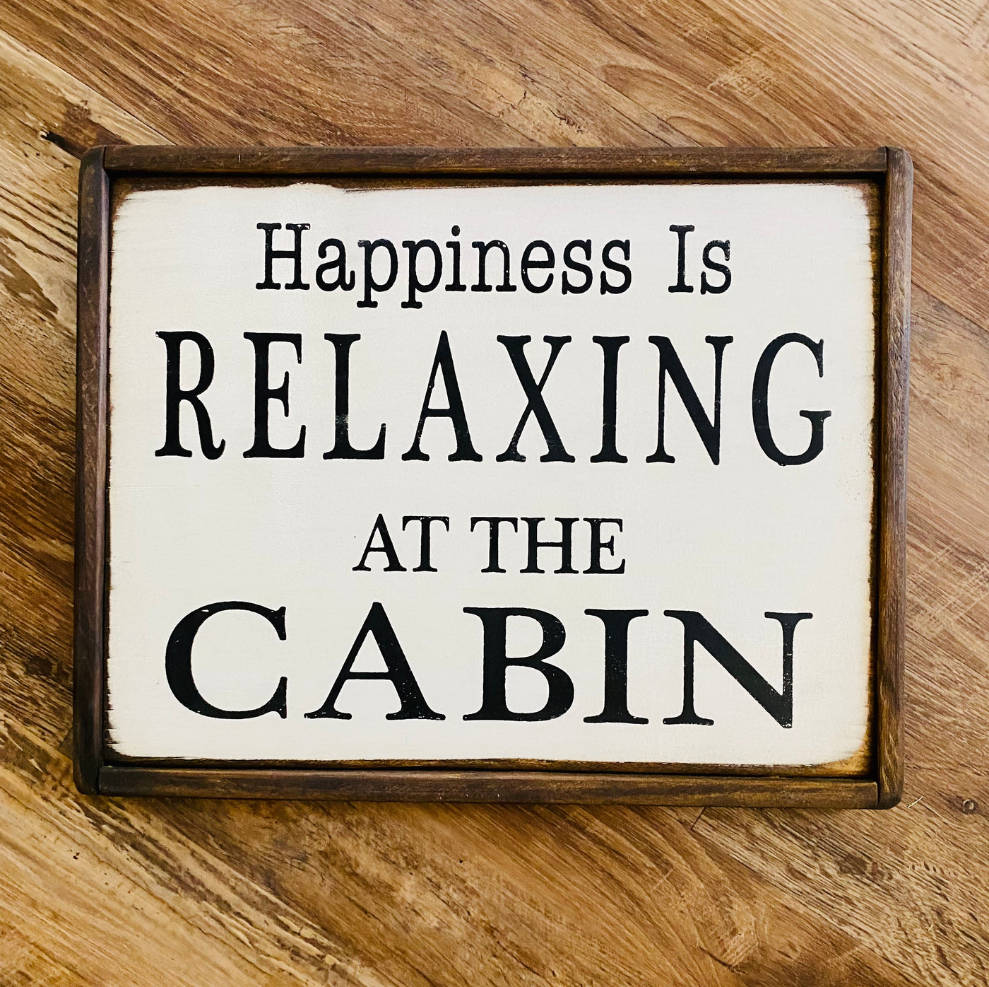 Handmade wooden sign reads happiness is relaxing at the cabin