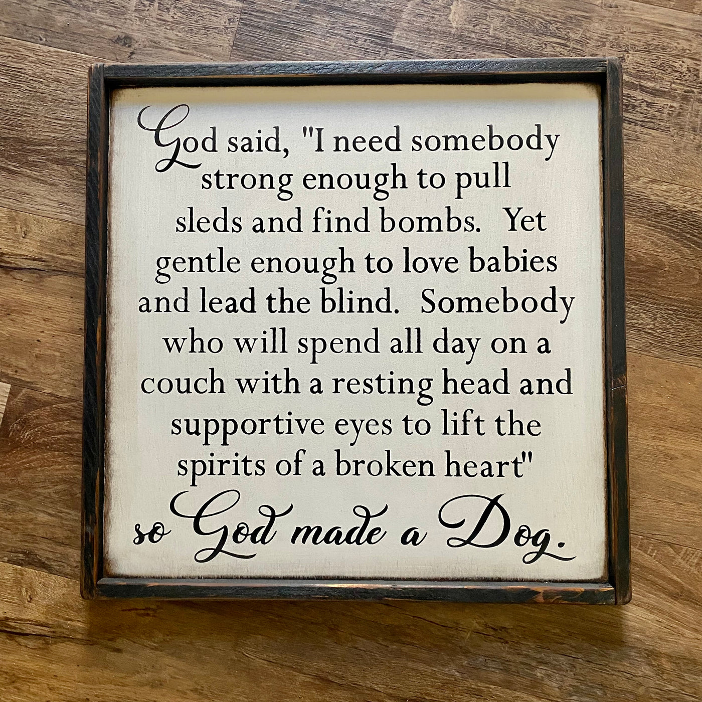 handmade wood sign reads God said, I need somebody strong enough to pull sleds and find bombs. Yet gentle enough to love babies and lead the blind. Somebody who will spend all day on a couch with a resting head and supportive eyes to lift the spirits of a broken heart so God made a Dog.