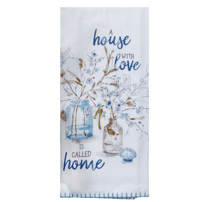 White towel printed with A House With Love Is Called Home, light blue embroider edge with images of jars filled with twigs and berries.Tan, blue, and grey hues. 
