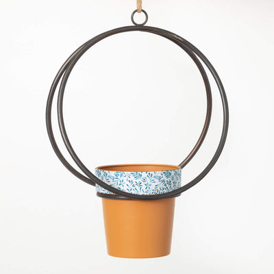 Round metal hanging frame holding a terracotta style planter