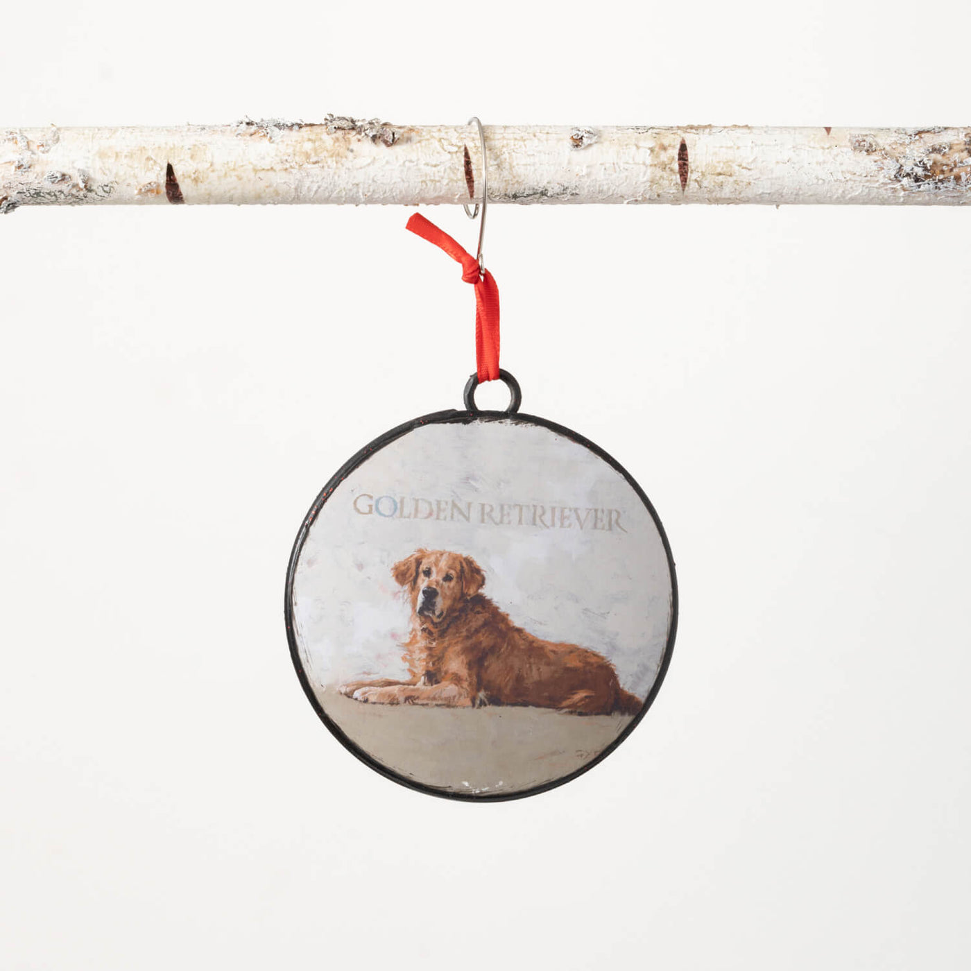 Round metal ornament with portrait of a Golden Retriever on the front and a red back. Comes with a red ribbon for hanging.