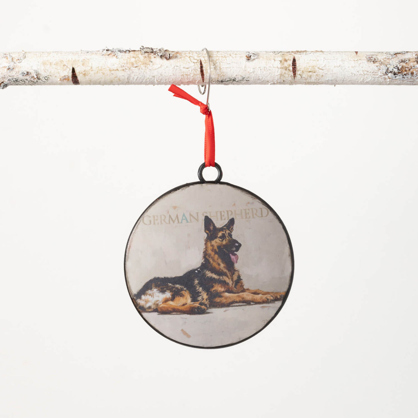Round metal ornament with a portrait of a German Shepherd on the front, back is red.  Comes with a red ribbon for hanging.
