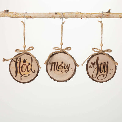 Three wood slice style ornaments with ripped ribbon and hanging string read Noel, Merry, and Joy