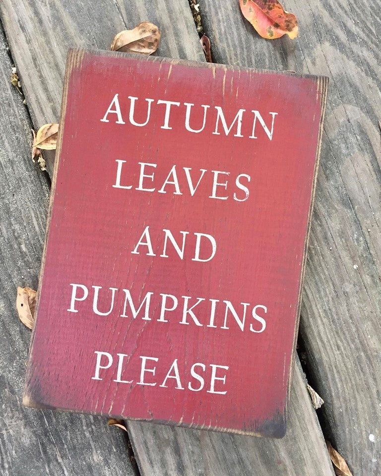 Handmade wood sign with a natural edge reads Autumn Leaves And Pumpkins Please in white lettering on a red background
