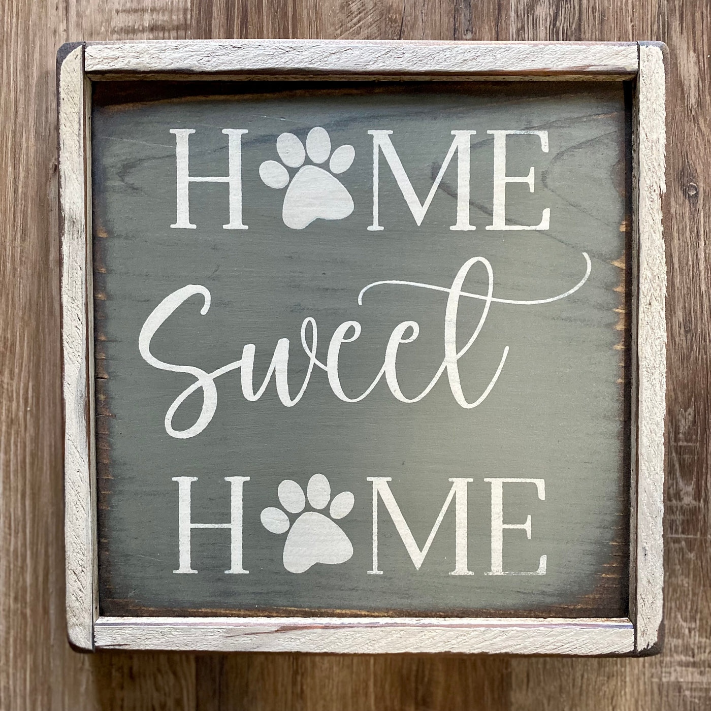 Handmade wood sign reads Home Sweet Home with paw prints in place of the “O” in Home