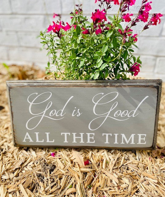 Handmade wood sign painted gray with white lettering that reads God Is Good All The Time