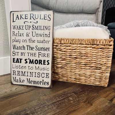 Handmade wood sign reads Lake Rules, Wake Up Smiling, Relax & Unwind, Play on the water, watch the sunset, sit by the fire, Eat S’mores, Listen to Music, Reminisce, Make Memories