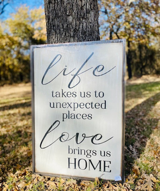 Large, handmade wood sign reads life takes us unexpected places, love brings us home