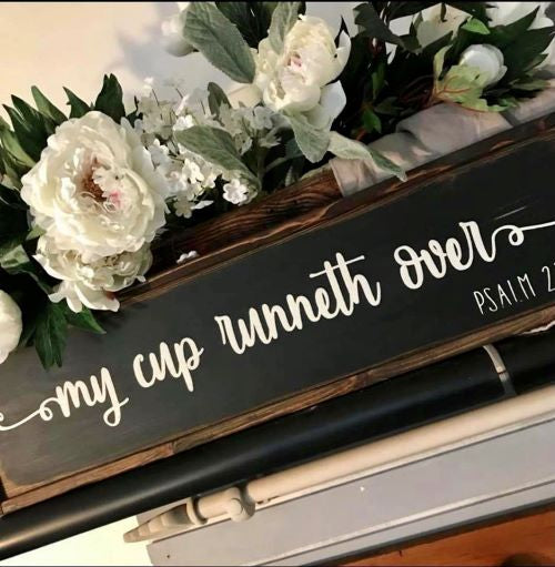 Wooden sign that reads "My Cup Runneth Over". Sign is framed.