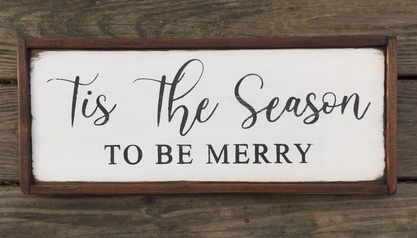 Handmade wooden holiday sign reads this the season to be merry. White background with black lettering. 
