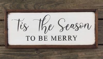 Handmade wooden holiday sign reads this the season to be merry. White background with black lettering. 