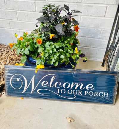 Handmade wooden blue sign with decorative edge reads Welcome To Our Porch